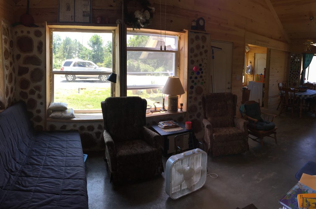 Inside the living room of our cordwood home. Its still a work in progress! Find out the answers to the most common questions we hear in this post #alternativebuilding #naturalbuilding #cordwoodmasonry