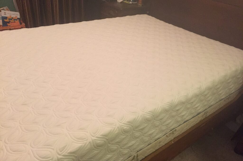 Our old white Sealy Cocoon memory foam mattress from 2016 on a wooden bed frame with a box spring