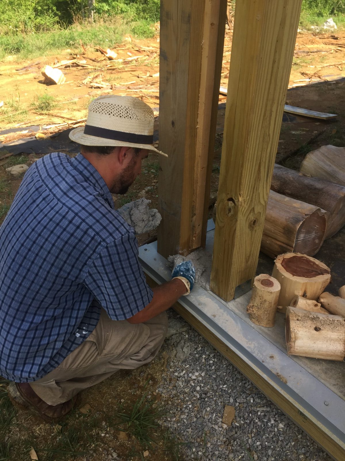 Man in white hat preparing to lay cordwood wall in a small column